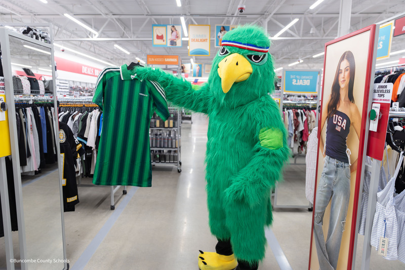 The Haw Creek Hawk holds up a green shirt inside Burlington.