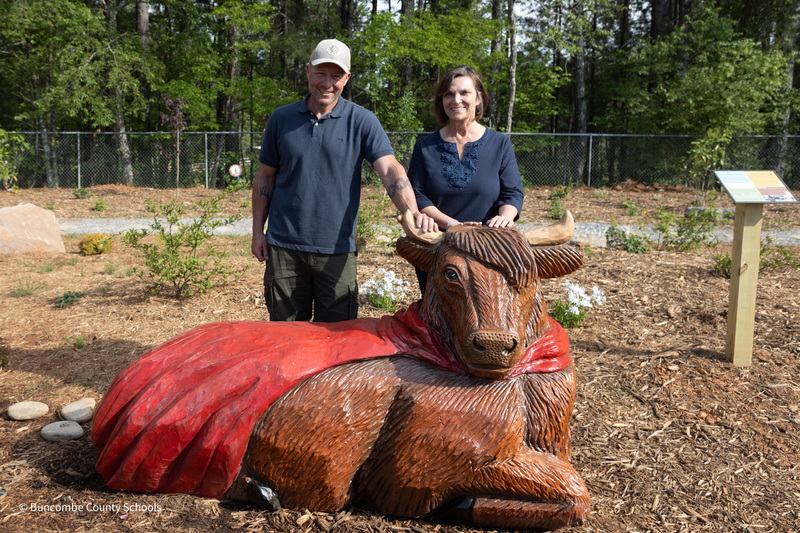 The artist and a friend stand behind the cow sculpture.