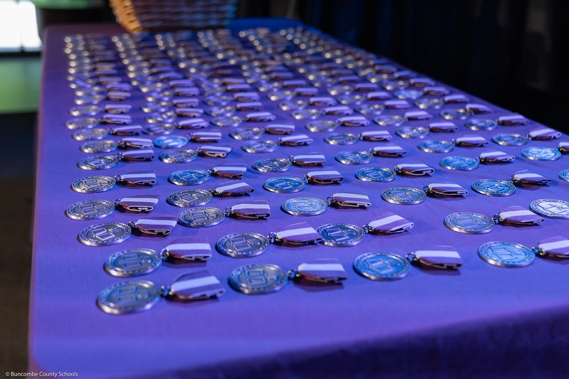 A shot of the Top Scholar medals arranged in rows on a purple tablecloth