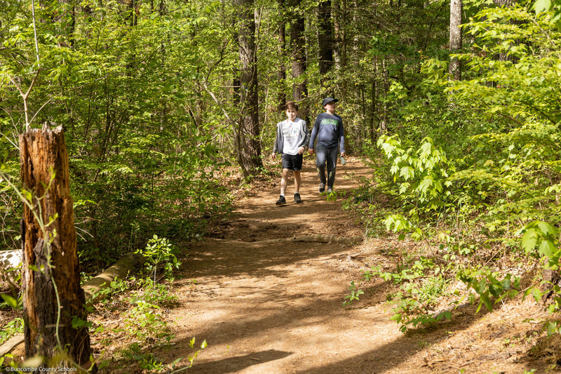 Two boys walk down a trail.