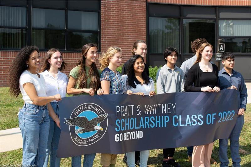A group of students holding a scholarship banner