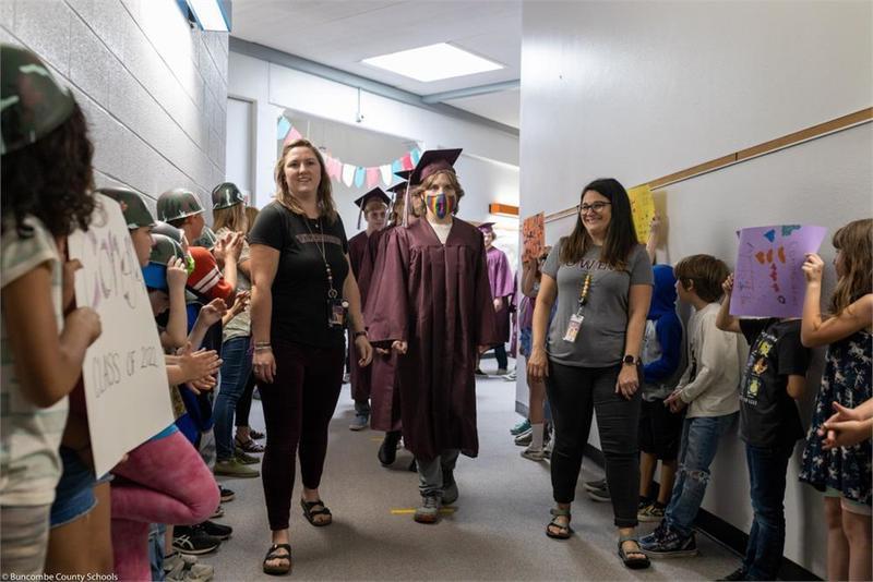 Students walking down the hall past younger students Students walking down the hall past younger students
