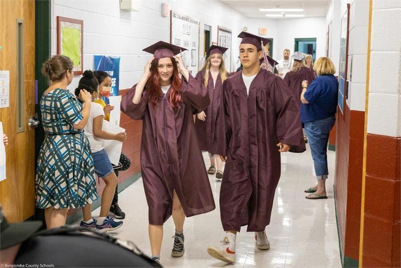 Graduates walking down the hall past students Graduates walking down the hall past students