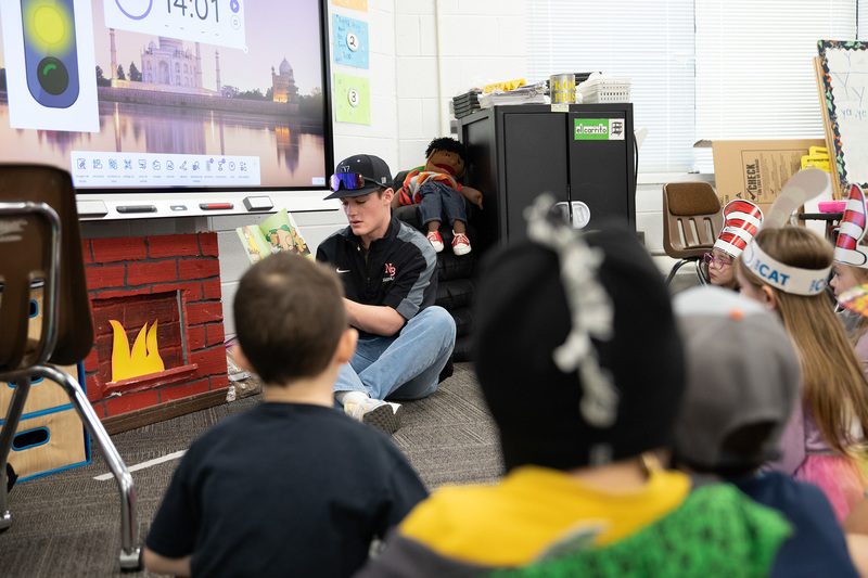 Baseball player reading to a group of Kindergarteners.