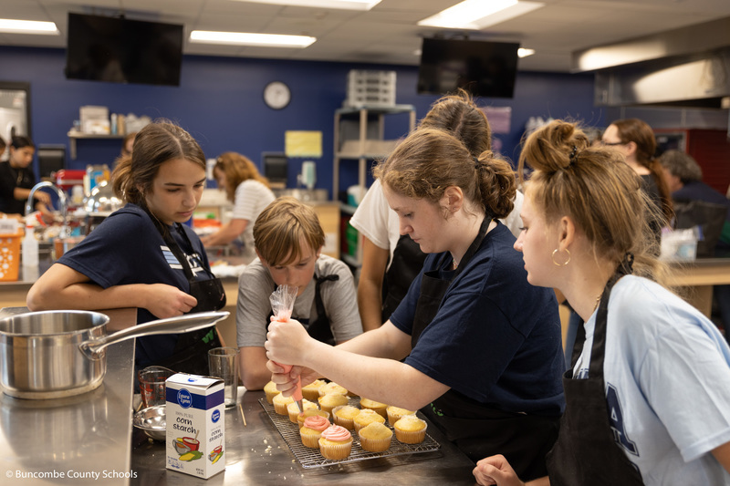 Students icing cupcakes. 
