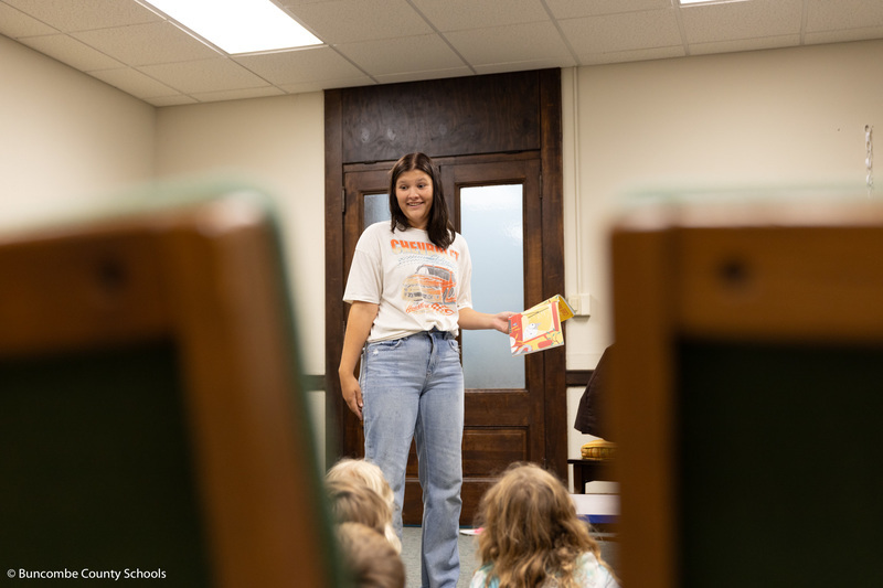 High school student reading to a group of campers. 