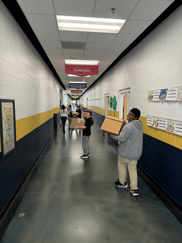 Students carrying boxes of socks through the school. 
