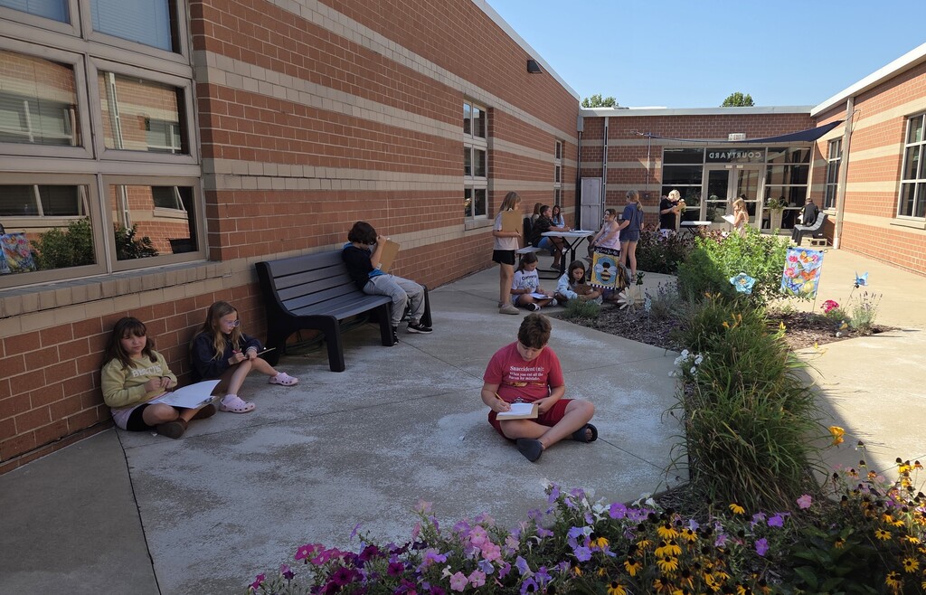 Wide view of many students drawing in the courtyard.