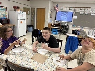 Students are smiling while eating s'mores.