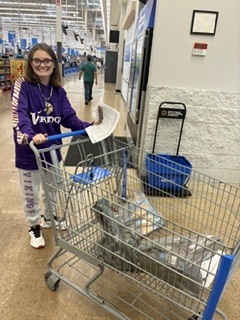 A student is pushing a shopping cart and smiling.