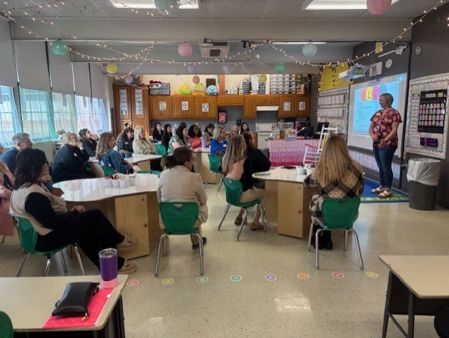 Image shows a principal speaking to group.