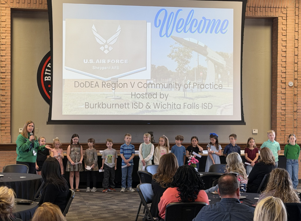 Image shows second graders speaking before guests.