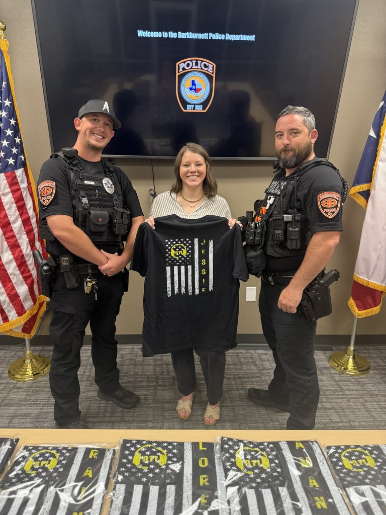 Chief McDonald and Lt. Deason giving Burkburnett PD Dispatcher Jessie a custom shirt.