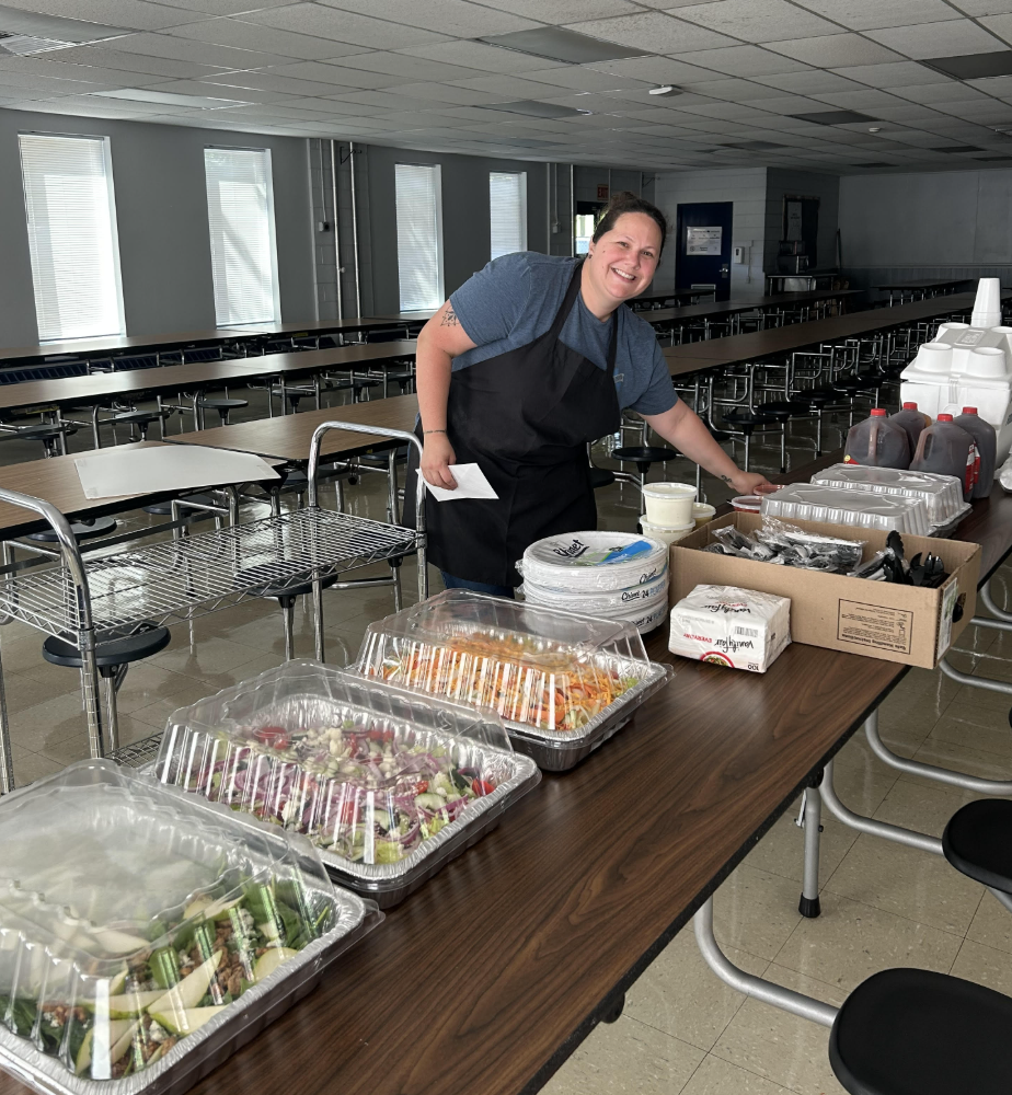 Person in a cafeteria organizing a trays of food. 