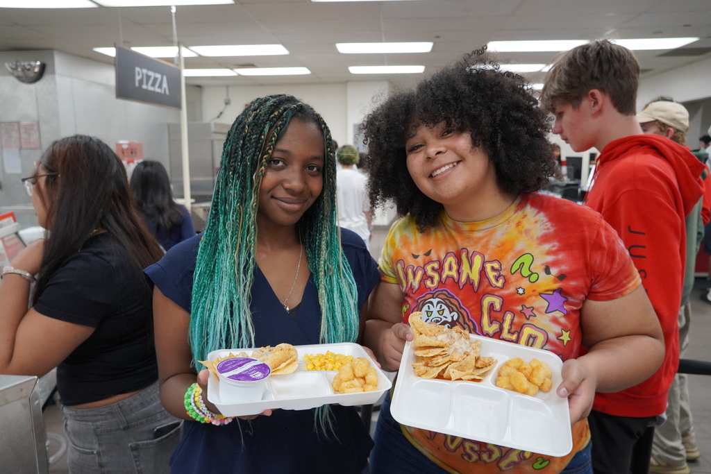 students smiling with lunch trays of nachos