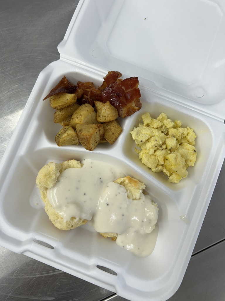 a tray of eggs, bacon, potatoes and gravy biscuit
