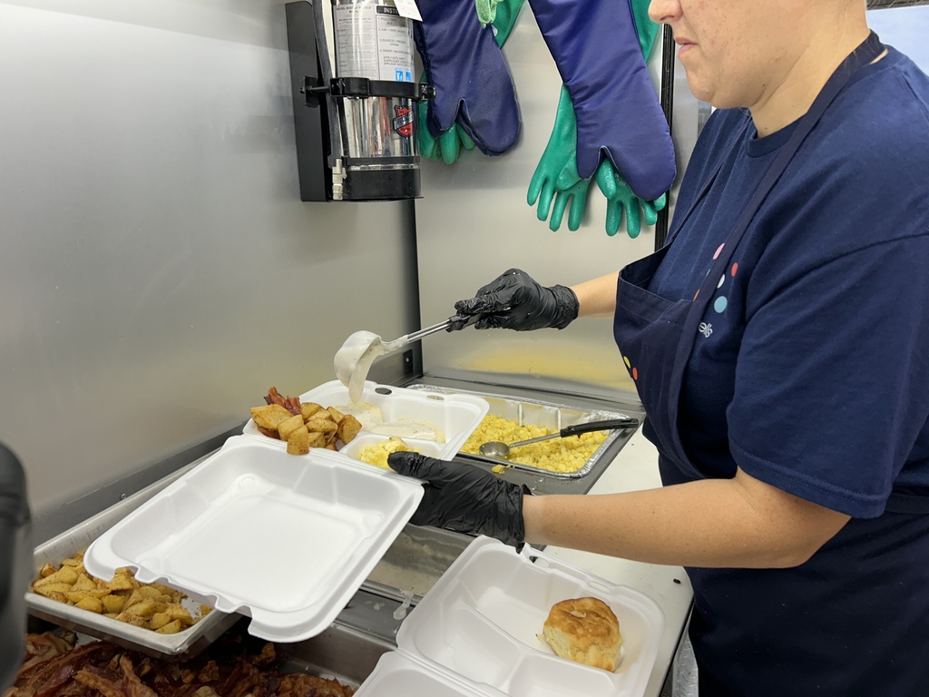 staff adds gravy to a biscuit on the tray
