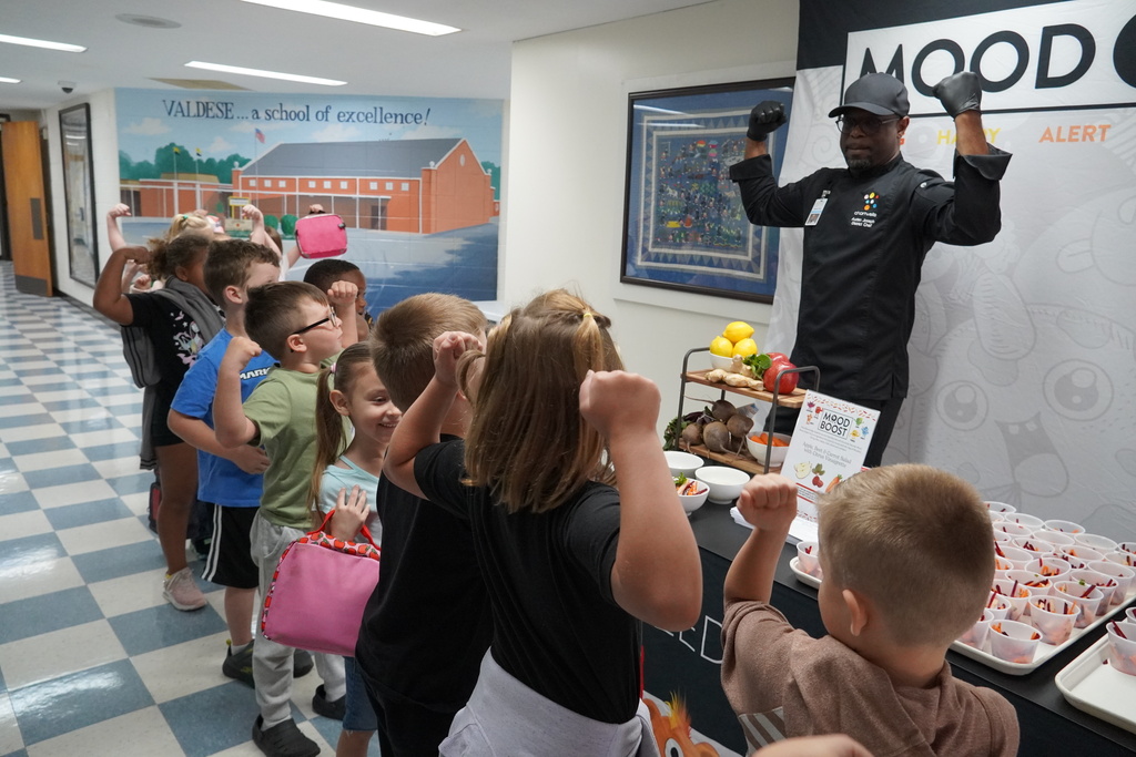 chef holding up muscle arms for Mood Boost event to children