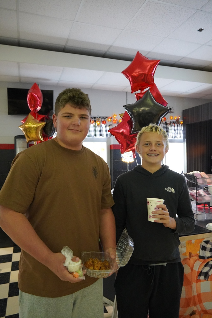 students hold a coffee and wings from the coffee shop