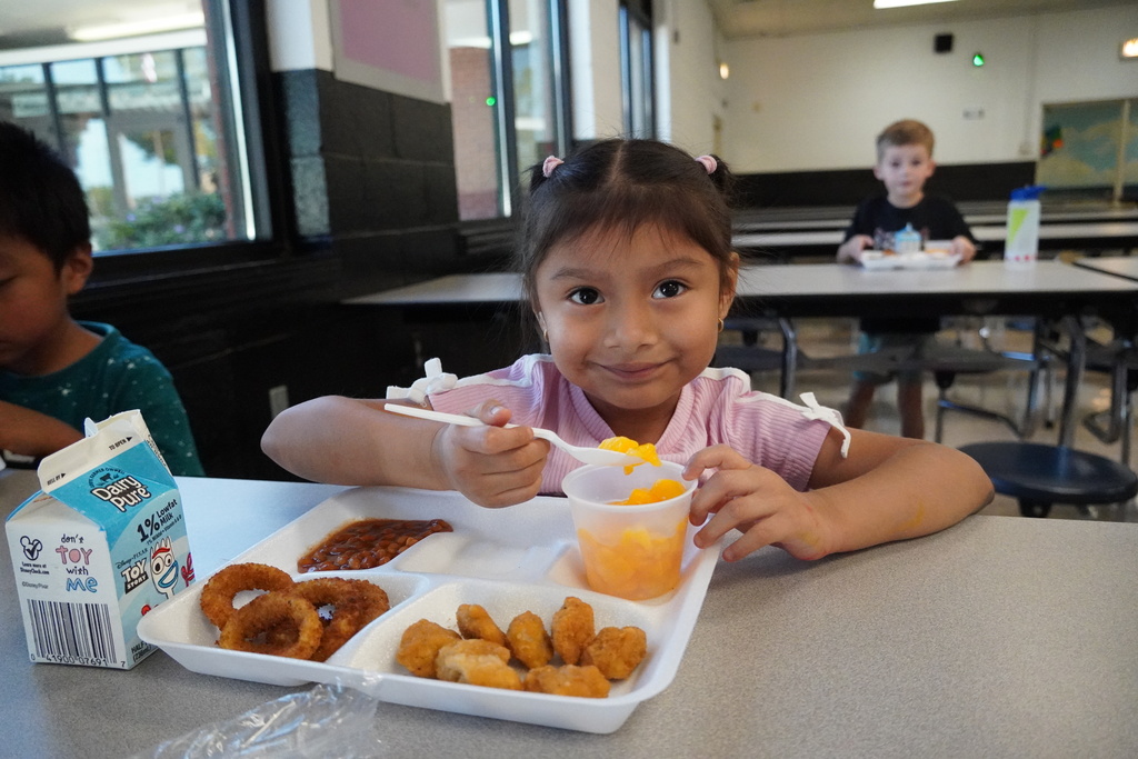 student smiling with spoonful of peaches