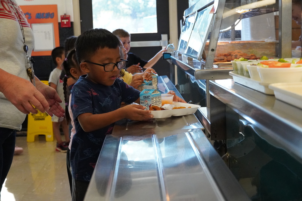 student holds tray on serving line