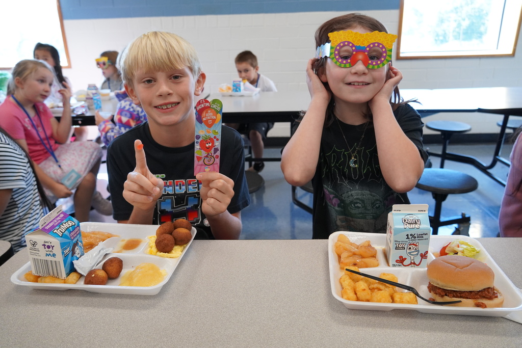 students hold their prizes with their lunch. trays