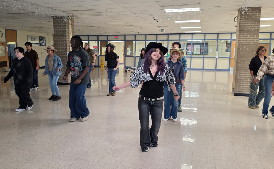 Students line dancing. One student with a black cowboy hat.