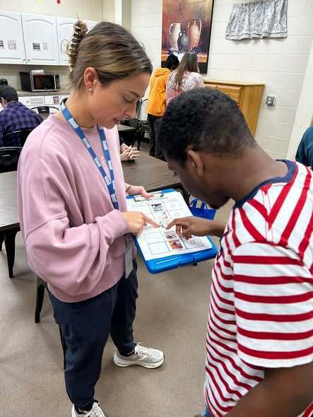 Transition teacher working with student on AAC device.