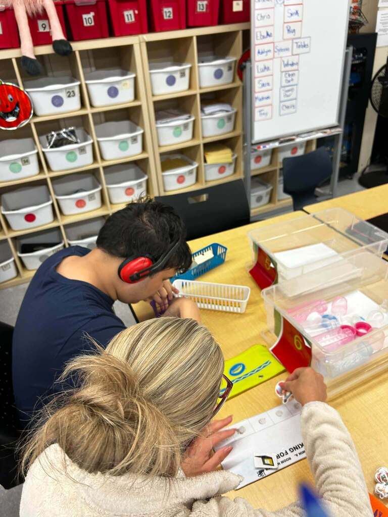 Student with head phones working alongside teacher