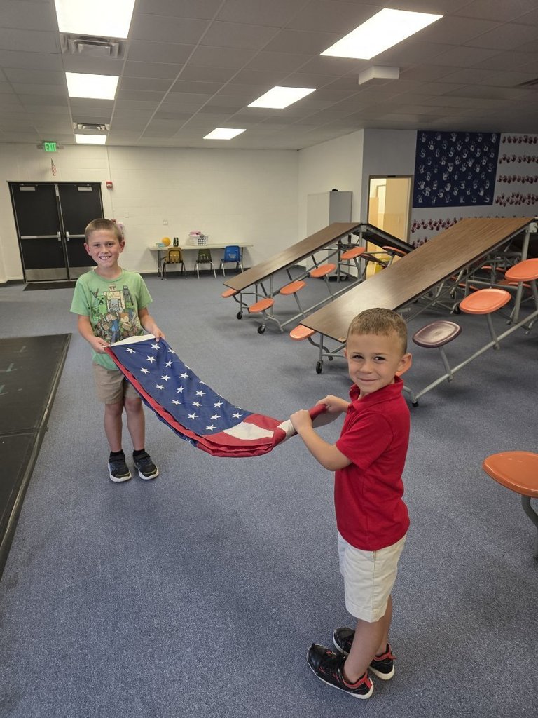 two students helping fold the American Flag.