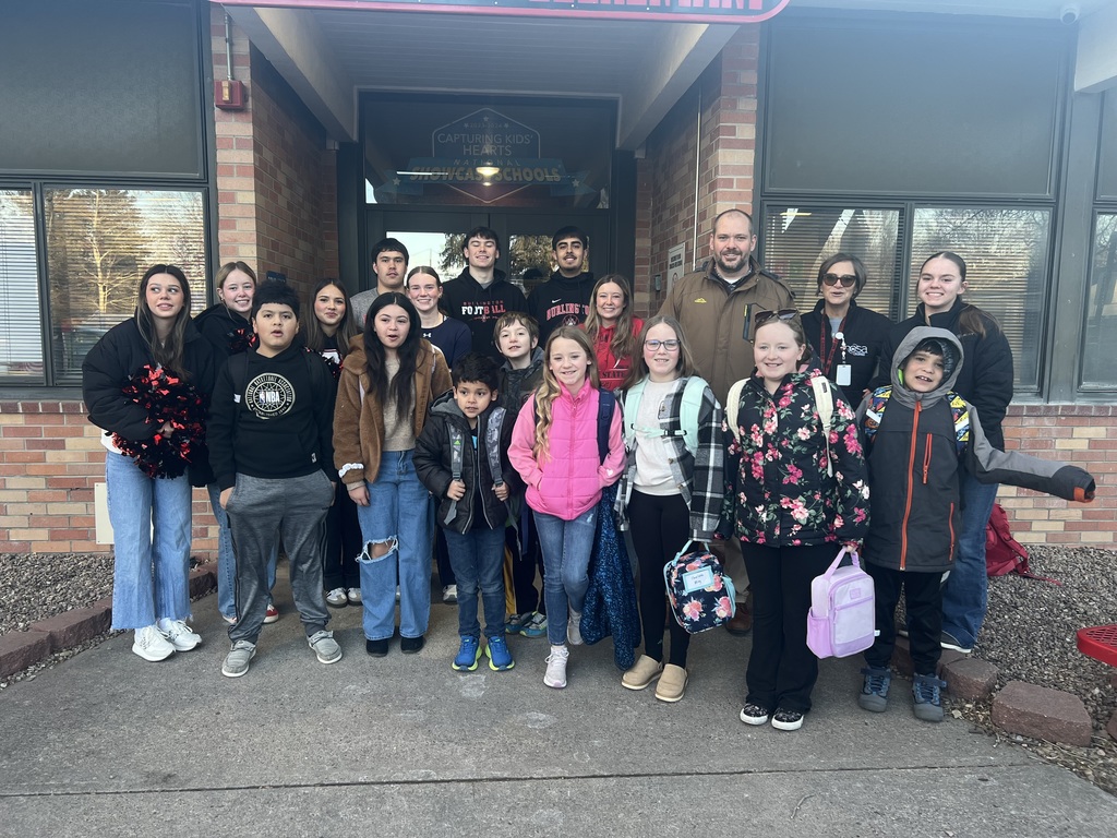 High schoolers helping greet kids at elementary school. 