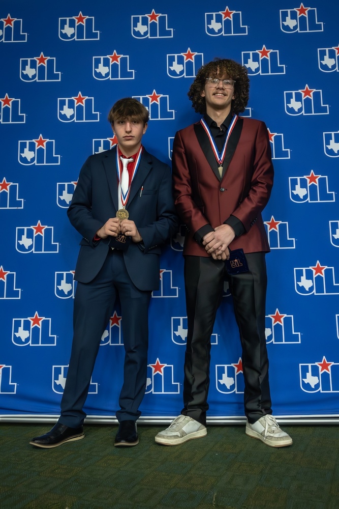 2 boys standing in front of UIL background