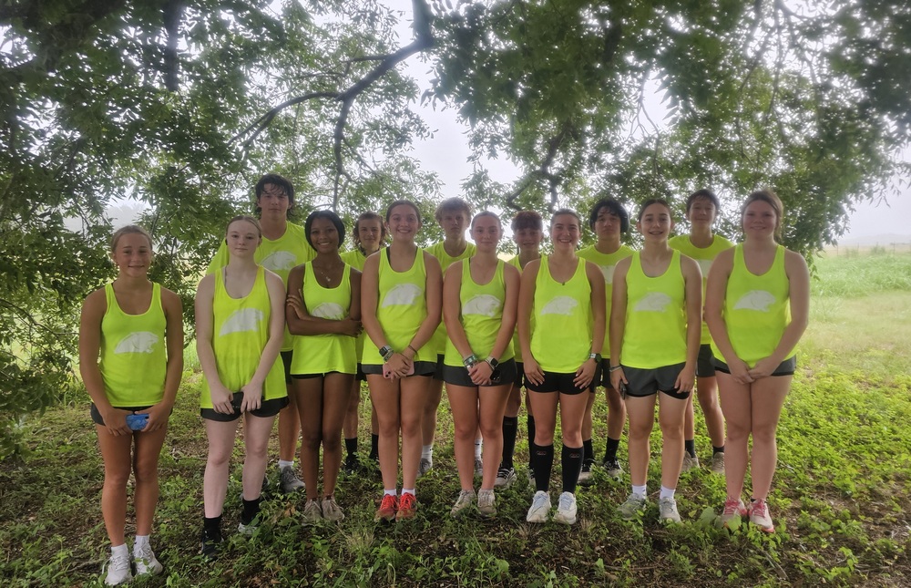 Group of students in neon tank tops and black shorts smiling at the camera