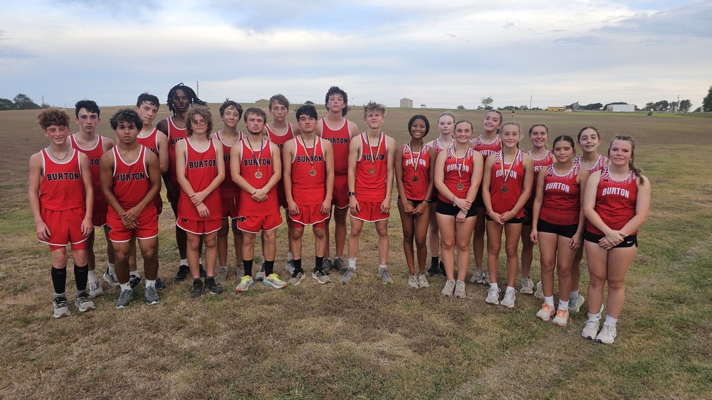 group of boys and girls in red tank tops & shorts all smiling at the camera.