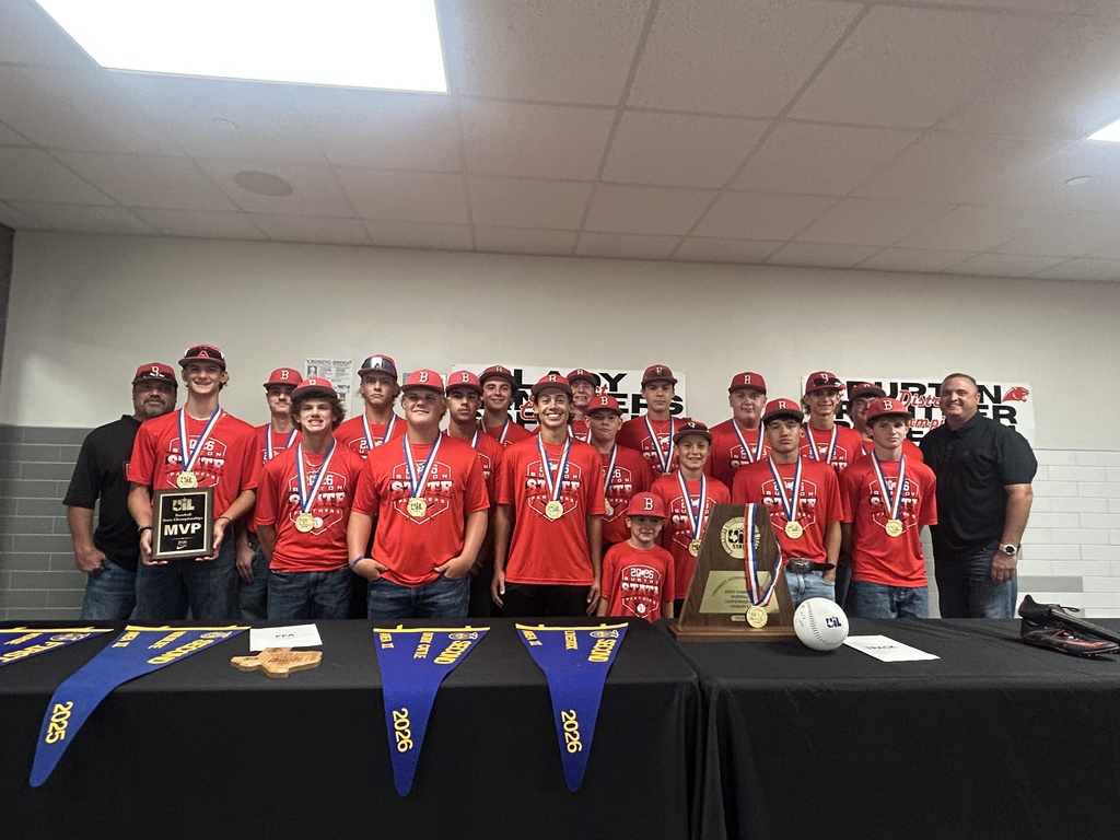 group of boys in red tshirts and medals flanked by 2 men in black all smile at the camera.