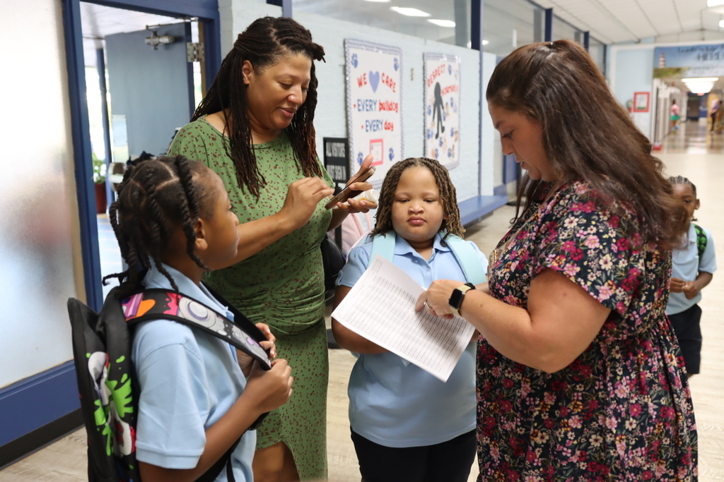 Teachers help students locate their classes on the first day of school