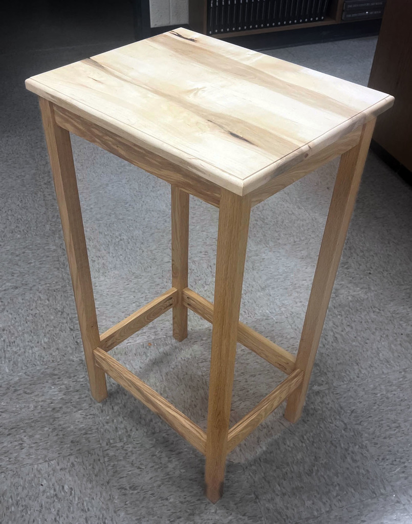 A photo of a tall, slender. and modern wooden coffee/end table. 