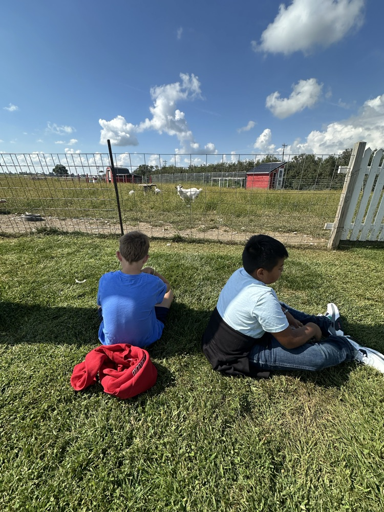 A group of 5th graders enjoying reading by the farm. 