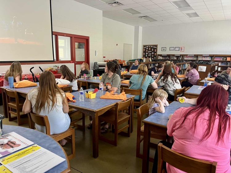 Group of people sitting at tables watching a video