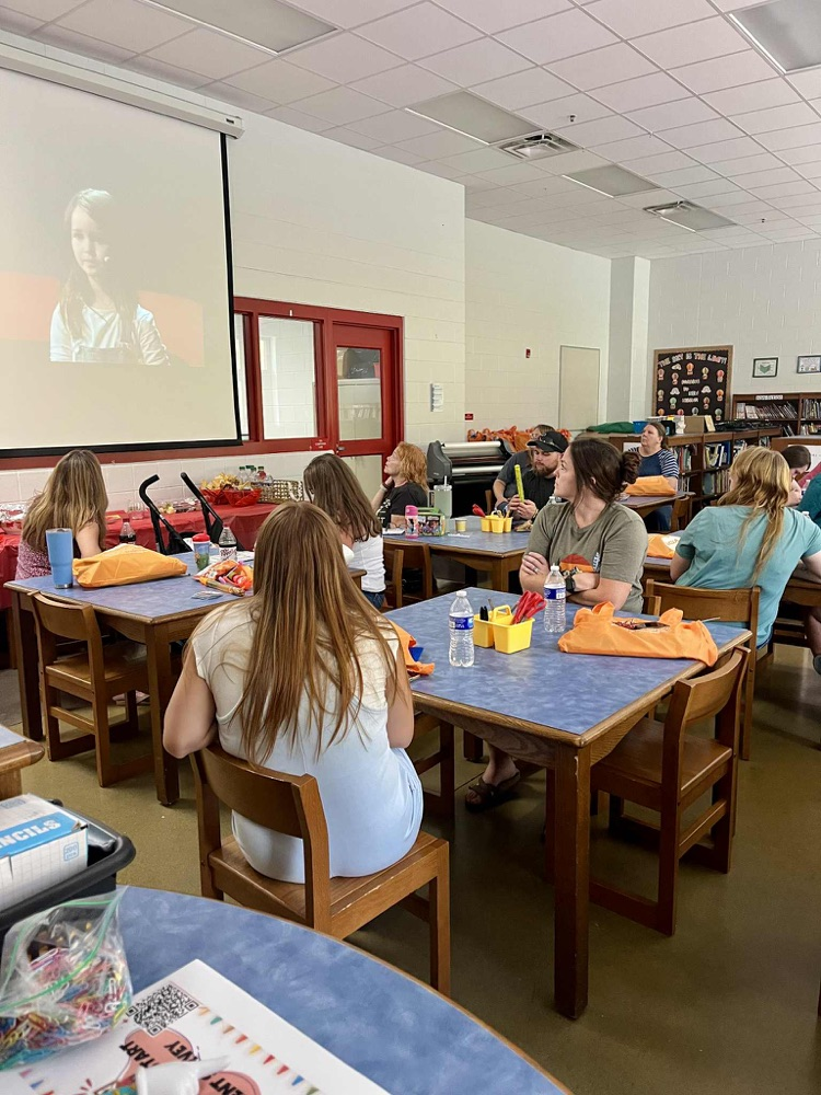 Group of people sitting at tables watching a video