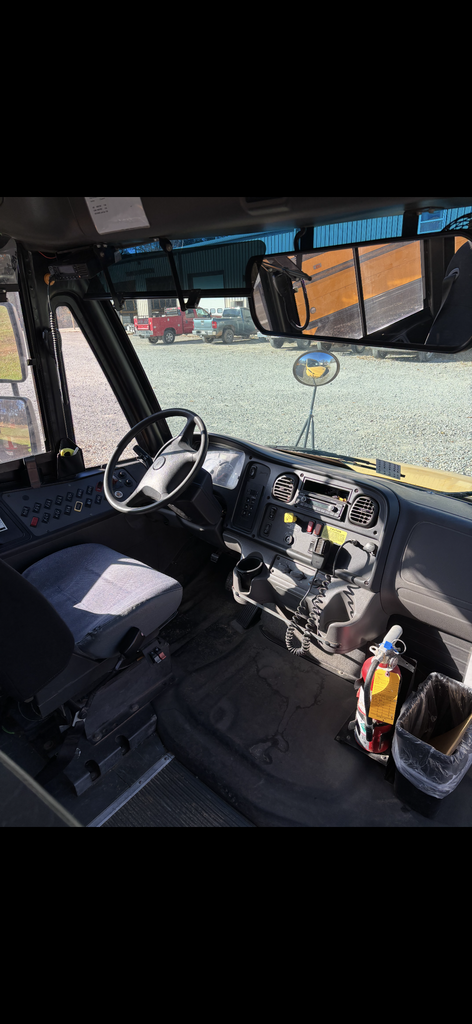 For surplus Bus 12 Thomas Freightliner inside view of bus. Driver's seat, dash, windsield, steering wheel.