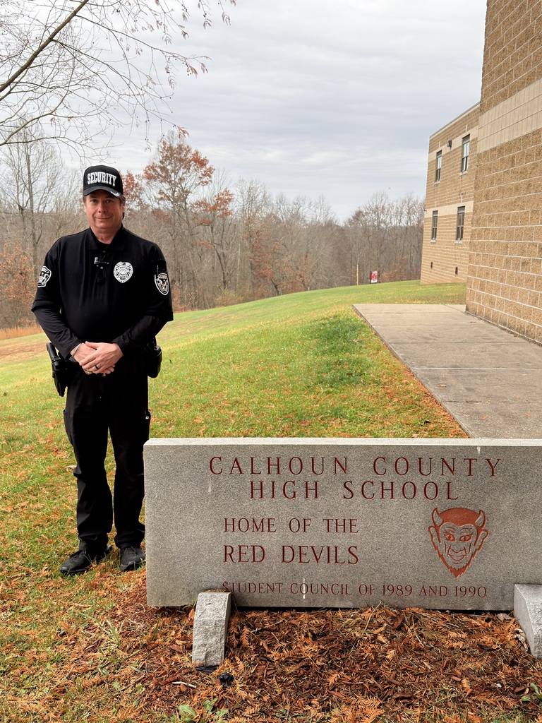 School Security officer standing beside sign.