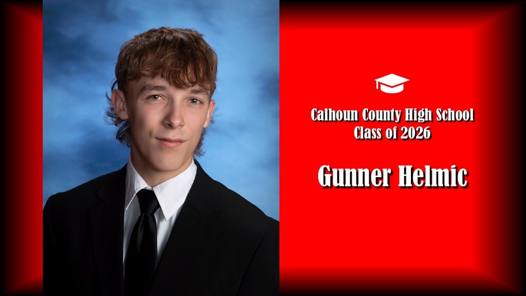 A formal senior portrait layout featuring a student with medium-length wavy hair, wearing a black suit jacket, white shirt, and dark tie, posed against a blue studio background on the left. The right side displays a bright red panel with a graduation cap icon and white text that reads “Calhoun County High School Class of 2026” and the name “Gunner Helmic” in large bold letters.
