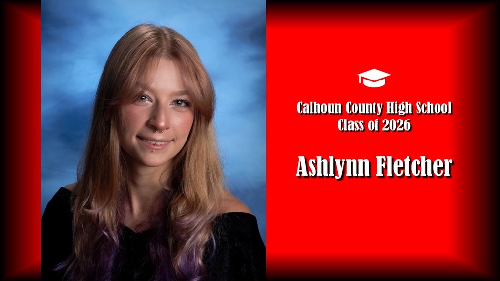 A formal senior portrait layout featuring a student with long layered hair that transitions to a lighter tone at the ends, wearing a black off-the-shoulder top, posed against a blue studio background on the left. The right side shows a bright red panel with a graduation cap icon and white text that reads “Calhoun County High School Class of 2026” and the name “Ashlynn Fletcher” in large bold letters.