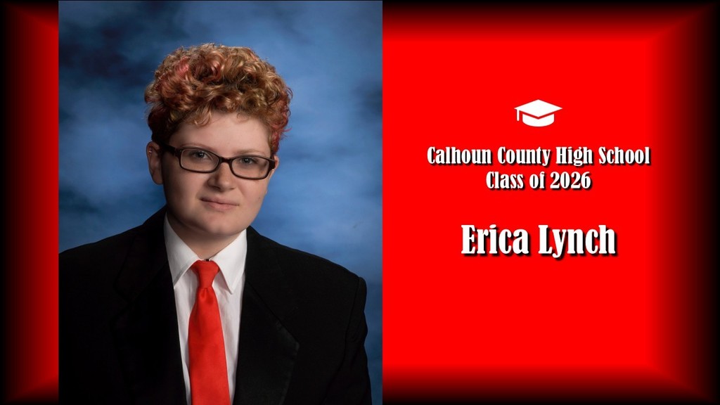 A formal senior portrait layout featuring a student with short curly hair tinted with red highlights, wearing glasses, a black suit jacket, white shirt, and red tie, posed against a blue studio background on the left. The right side displays a bright red panel with a graduation cap icon and white text that reads “Calhoun County High School Class of 2026” and the name “Erica Lynch” in large bold letters.