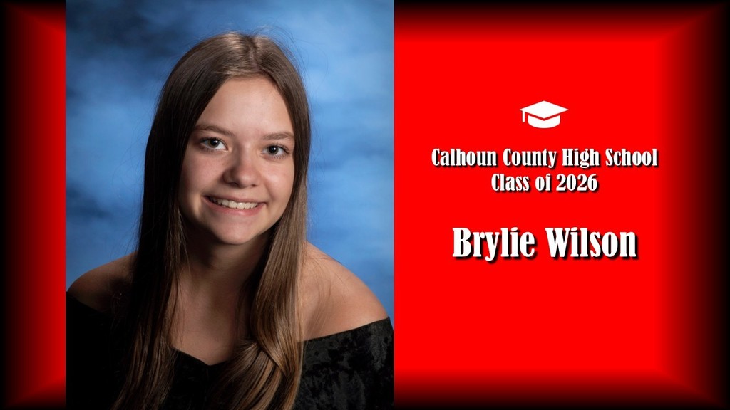 A formal senior portrait layout featuring a student with long straight brown hair, wearing a black off-the-shoulder top, posed against a blue studio background on the left. The right side displays a bright red panel with a graduation cap icon and white text that reads “Calhoun County High School Class of 2026” and the name “Brylie Wilson” in large bold letters.