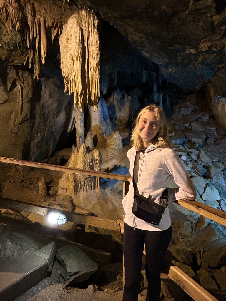 Student standing on a rail in a cave located in WV