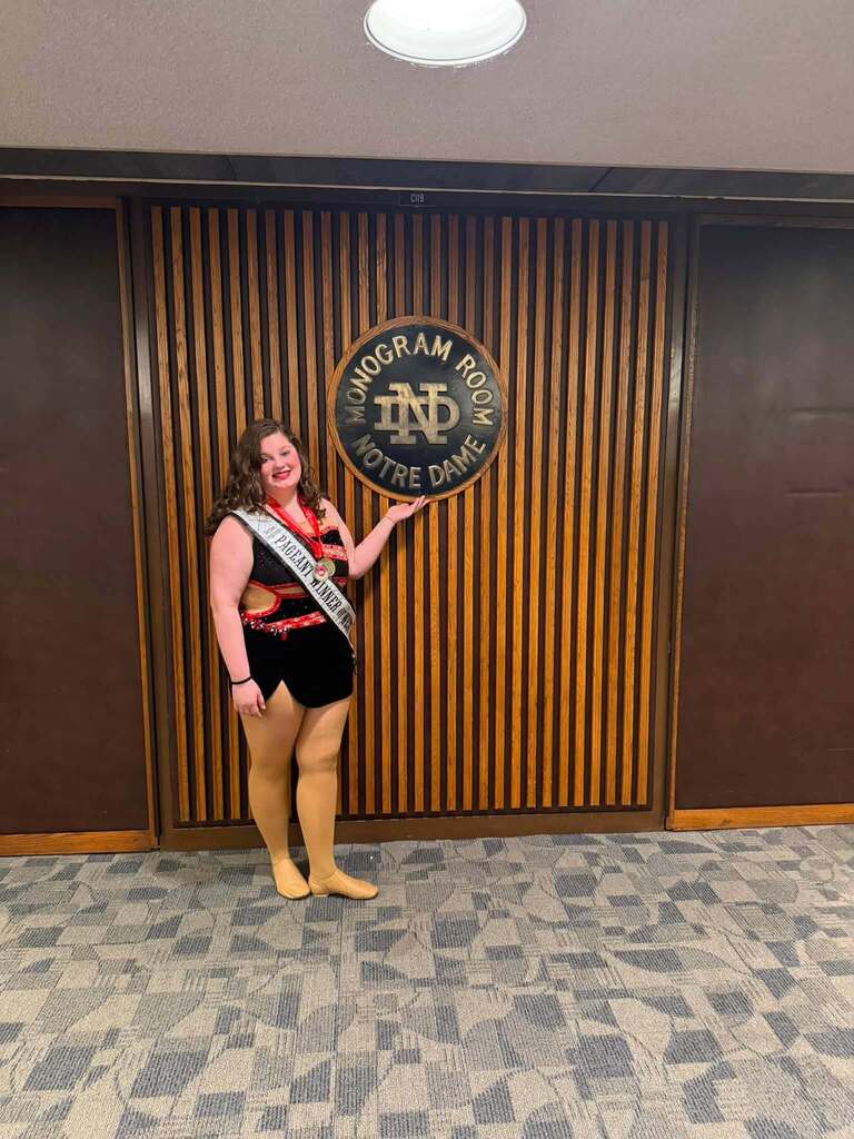 Sara stands at the Monogram room with medals she earned