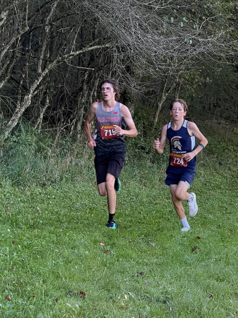 Jackson runing through the woods, neck and neck with  runner from  Faith Christian. 