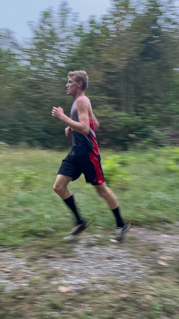Eli Ferrell runing  on the trail with trees behind him. 